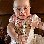 Blair joined the competition — help win amazing prizes! baby, infant, smiling, face, onesie, minnie_mouse, clothing, couch, leather_couch, arm, hand, rosy_cheeks, sitting, portrait, cheerful, eyes, blanket, indoor, happy, baby_girl