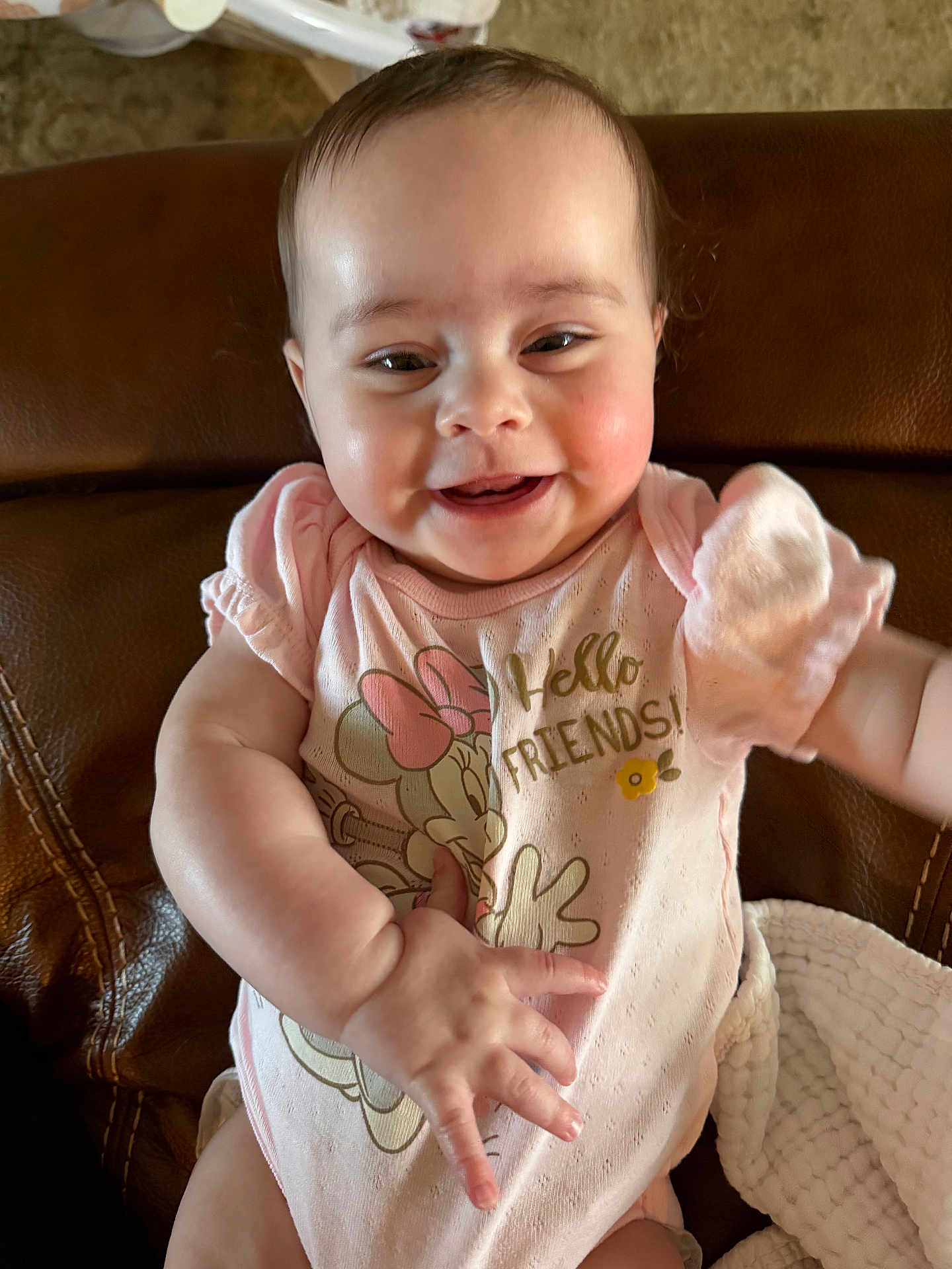 Blair joined the competition — help win amazing prizes! baby, infant, smiling, face, onesie, minnie_mouse, clothing, couch, leather_couch, arm, hand, rosy_cheeks, sitting, portrait, cheerful, eyes, blanket, indoor, happy, baby_girl