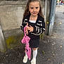 Varvara Bachmaha participe au concours pour gagner de l'argent avec cette photo : child, girl, umbrella, black_cardigan, white_bow, white_socks, white_shoes, sidewalk, outdoor, smiling, long_hair, holding_object, concrete_wall, black_skirt, fashion, cute, portrait, standing, daylight, urban