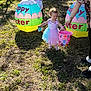 child, toddler, girl, easter, easter_egg, easter_basket, outdoor, grass, sunlight, inflatable, bunny, egg, toy, dress, person, adult_hand, bucket, festival, holiday, spring