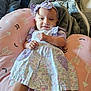 baby, child, infant, smile, dress, headband, purple, pink, cushion, blanket, indoor, person, cozy, comfort, pattern, arrow, relaxing, cute, young, happy