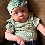 Adilynn is registered to the contest to win money with this photo: baby, casual, child, clothing, couch, cute, expression, fabric, flower, green_shirt, headband, indoor, infant, jeans, portrait, relaxed, sitting, skin, small_hand, soft_light