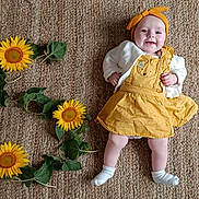 Rosalya participe au concours pour gagner de l'argent avec cette photo : baby, child, smiling, yellow_dress, headband, sunflowers, green_leaves, woven_rug, indoor, laying_down, happy, cute, infant, white_socks, natural_light, portrait, flower_arrangement, celebration, number_three, skin