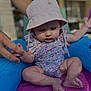 baby, child, inflatable_pool, hat, floral_clothing, hand, water, summer, outdoor, infant, skin, foot, leg, sitting, cute, sun_hat, person, childhood, toddler, colorful