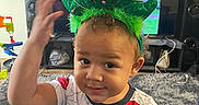 Isaiah is registered to the contest to win money with this photo: child, toddler, portrait, smiling, christmas, christmas_tree_hat, festive, spiderman, superhero, costume, indoors, living_room, television, teddy_bear, speakers, carpet, toy, raised_hand, short_hair, holiday