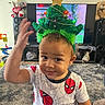 carpet, child, christmas, christmas_tree_hat, costume, festive, holiday, indoors, living_room, portrait, raised_hand, short_hair, smiling, speakers, spiderman, superhero, teddy_bear, television, toddler, toy
