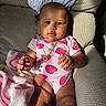 baby, blanket, child, close_up, clothing, couch, face, hands, home, infant, legs, necklace, outdoor_light, photography, pink, portrait, sitting, smiling, strawberry, sunlight
