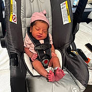 Saanvi is registered to the contest to win money with this photo: newborn, baby, car_seat, pink_hat, sleeping, infant, tiny_toes, hospital_bracelet, safety_harness, indoors, soft_lighting, cute, peaceful, child, person, baby_clothing, seat, resting, newborn_baby, closeup