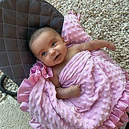 Raya is registered to the contest to win money with this photo: baby, blanket, pink, cushion, chair, face, infant, outdoor, gravel, soft_texture, satin, wrapped, cute, smile, person, young_child, skin, head, arm, foot