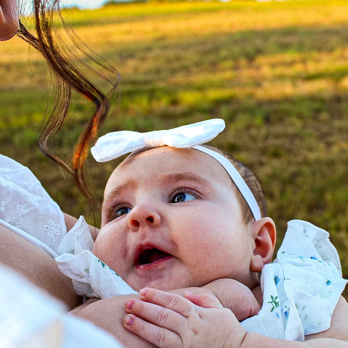 Taverly-Rose is registered to the contest to win money with this photo: baby, infant, child, woman, adult, face, headband, white_bow, smile, holding, outdoor, field, nature, grass, portrait, closeup, love, affection, skin, person