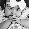 baby, infant, child, face, hands, bow, headband, black_and_white, portrait, close_up, expression, clothing, fabric, cute, young, sitting, person, soft_texture, curious, eyes