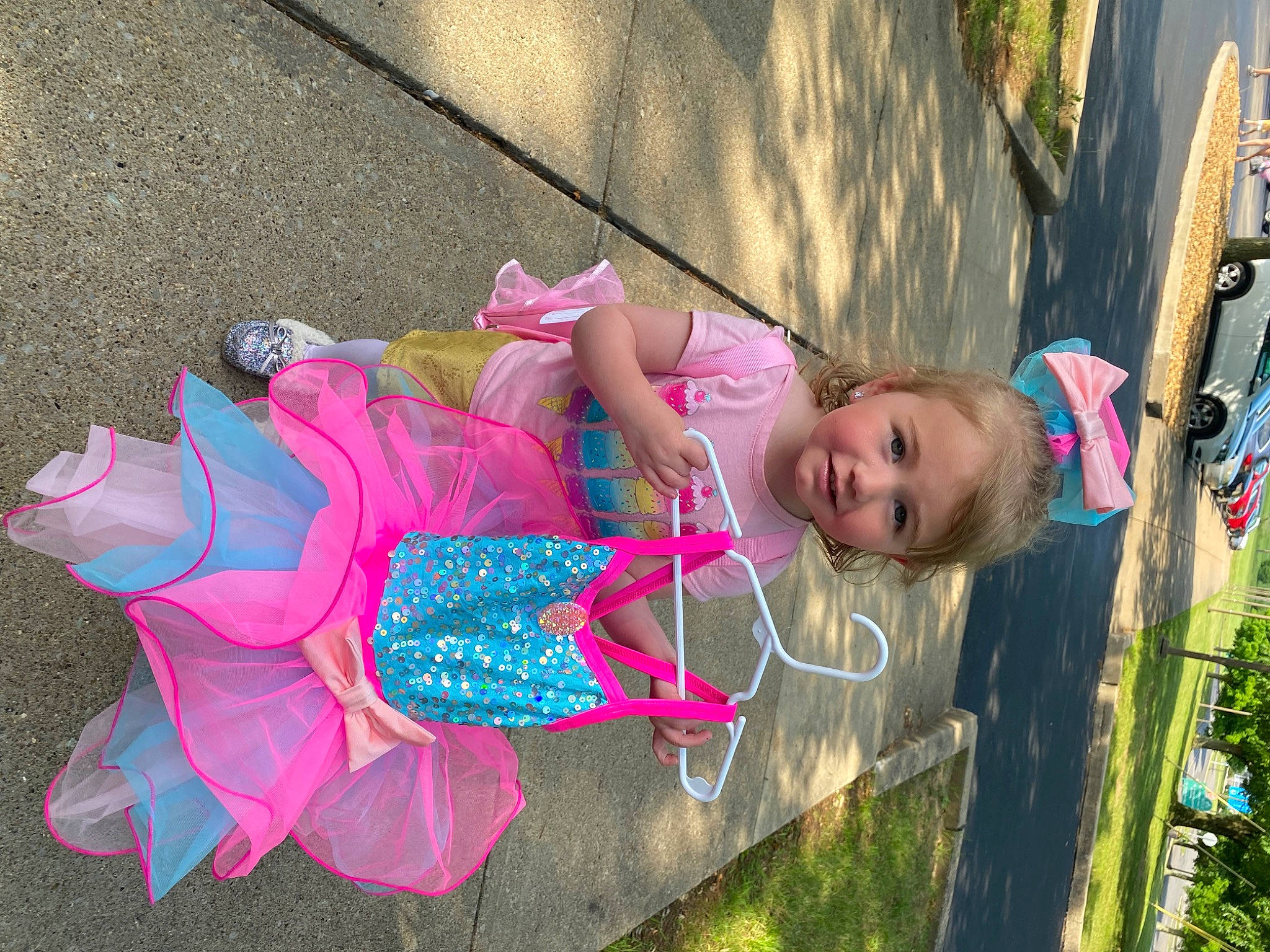 Gracie is registered to the contest to win money with this photo: asphalt, child, dress, event, fashion_accessory, fun, grass, happy, joy, leisure, magenta, pattern, person, pink, plant, product, recreation, sidewalk, sitting, summer