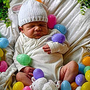 Silas is registered to the contest to win money with this photo: newborn, baby, sleeping, white_hat, knitted, easter_eggs, colorful, basket, blanket, booties, soft, cute, infant, resting, indoors, peaceful, small, cozy, hand, wrapped