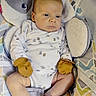 Silas is registered to the contest to win money with this photo: baby, child, clothing, comfort, cushion, expressionless, face, head, indoors, infant, legs, mittens, newborn, onesie, patterned, person, plush, seated, skin, soft