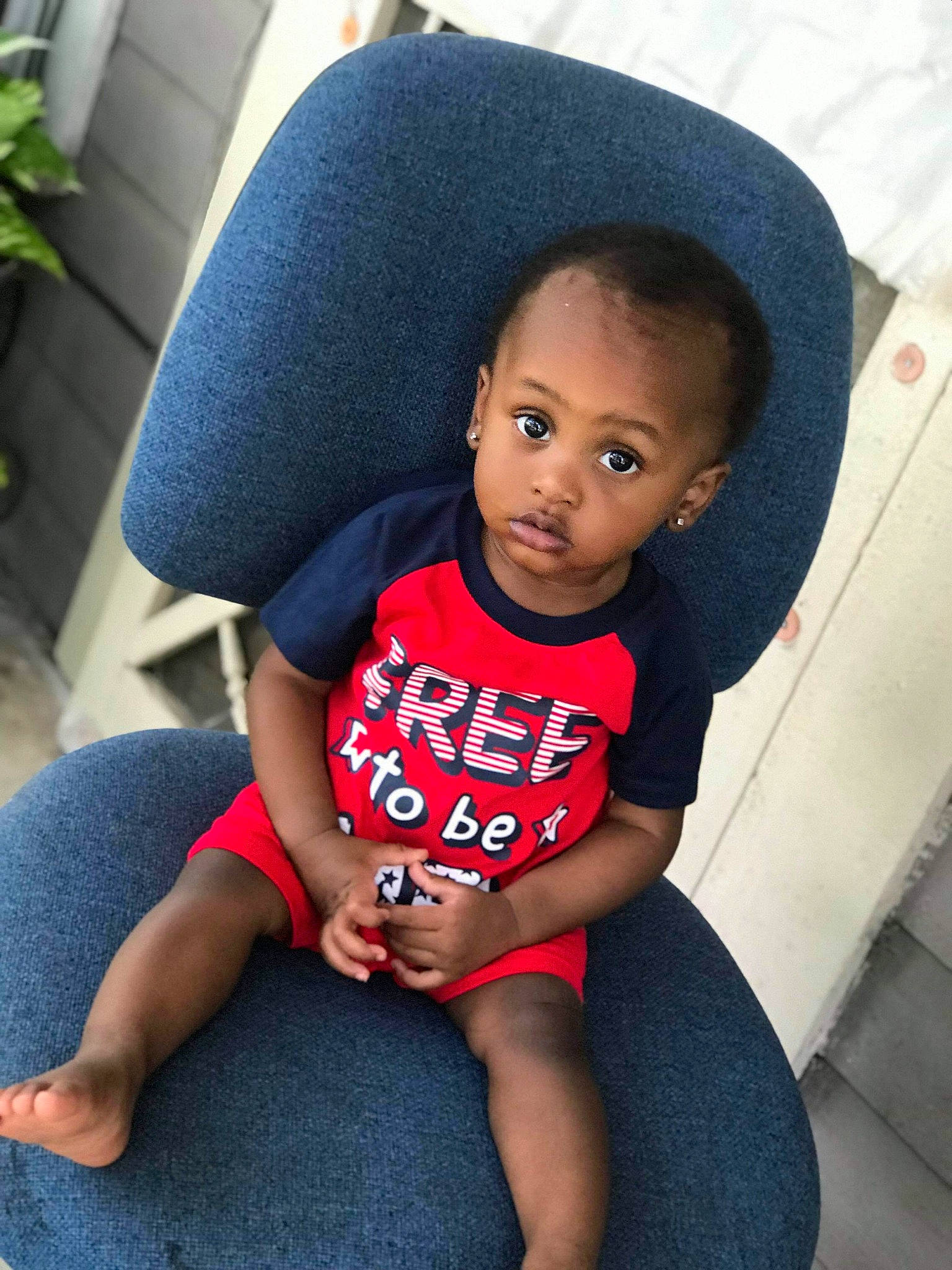 Kace is registered to the contest to win money with this photo: baby, black, black_hair, cheek, child, cool, face, head, leg, person, plant, sitting, skin, smile, t_shirt, thigh, toddler