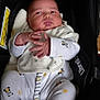 Ruby is registered to the contest to win money with this photo: baby, infant, car_seat, panda_pattern, onesie, white_clothing, hands, face, cheeks, footed_pajamas, sleepwear, child, cute, indoors, newborn, clothing_pattern, soft_toys, warning_label, black_background, portrait