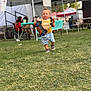 Jasper joined the competition — help win amazing prizes! toddler, child, toy, toy_car, grass, outdoor, tent, event, people, adult, chair, tree, clothing, shorts, shirt, footwear, daytime, play, walking, festival