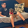 Chocolate joined the competition — help win amazing prizes! black_socks, blue_crocs, boy, casual, couch, dog, floor, furniture, glasses, home, indoor, living_room, pet, pillow, red_harness, relaxed, seated, shorts, tshirt, wood_paneling