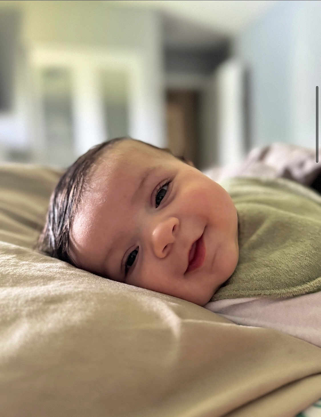 Zavier joined the competition — help win amazing prizes! baby, smiling, face, closeup, infant, lying_down, bib, soft_texture, indoors, head, skin, cheeks, eyes, hair, expression, person, portrait, young_child, cozy, background_blur