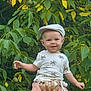Sohan participe au concours pour gagner de l'argent avec cette photo : baby, cap, child, cute, green_leaves, hand, happy, headwear, holding, infant, nature, outdoor, palm_tree_pattern, person, portrait, shirt, smile, summer_clothing, tree, young_child