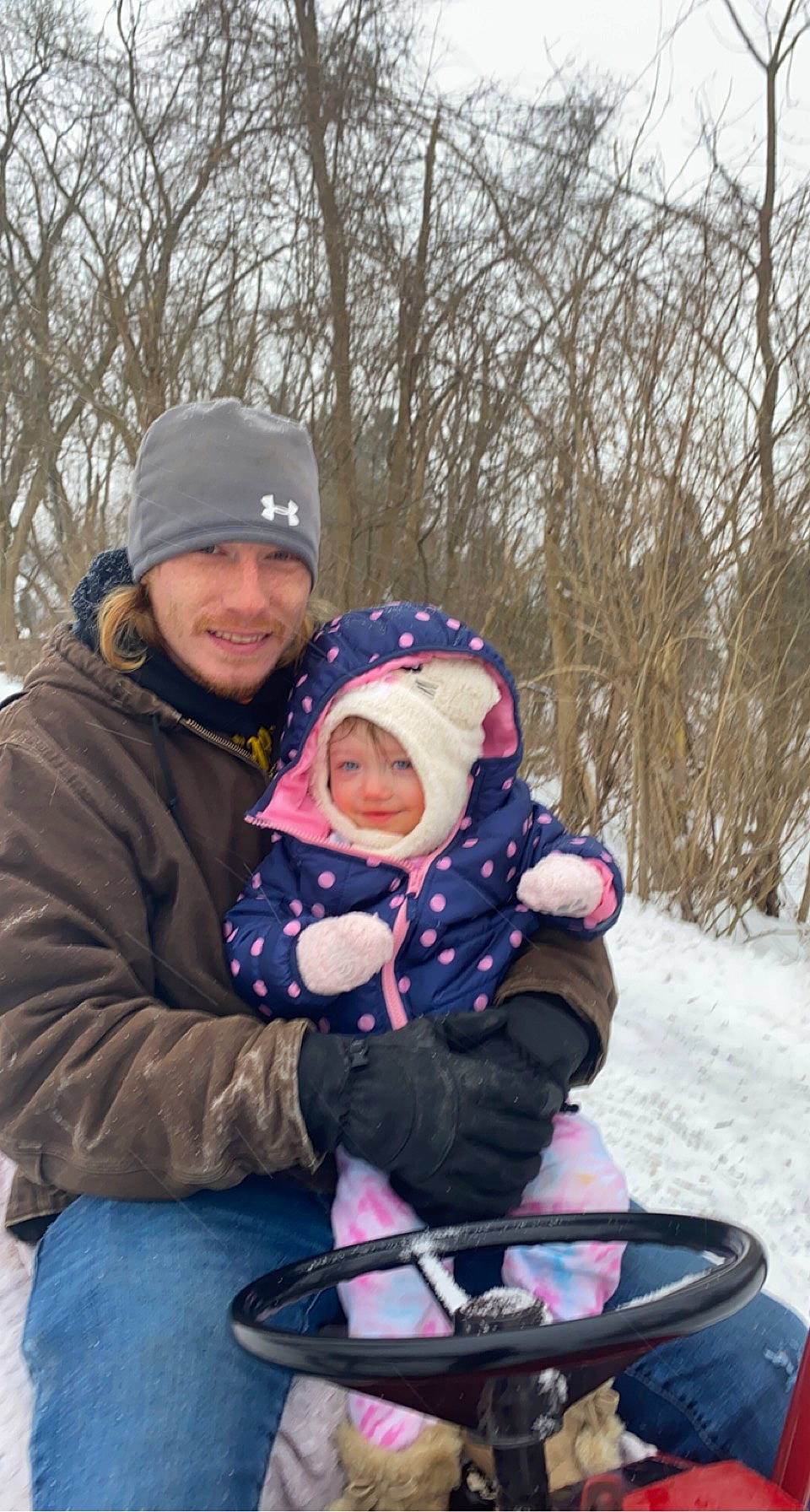 Elaina is registered to the contest to win money with this photo: baby, baseball_cap, cap, child, event, freezing, fun, happy, headwear, hoodie, jacket, joy, lap, leisure, outerwear, person, recreation, sitting, smile, snow