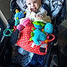 baby, child, stroller, infant, tongue_out, smiling, blue_eyes, portrait, toys, stuffed_animal, plush_toy, colorful, blanket, red, polka_dots, indoor, sitting, playtime, happy, baby_gear