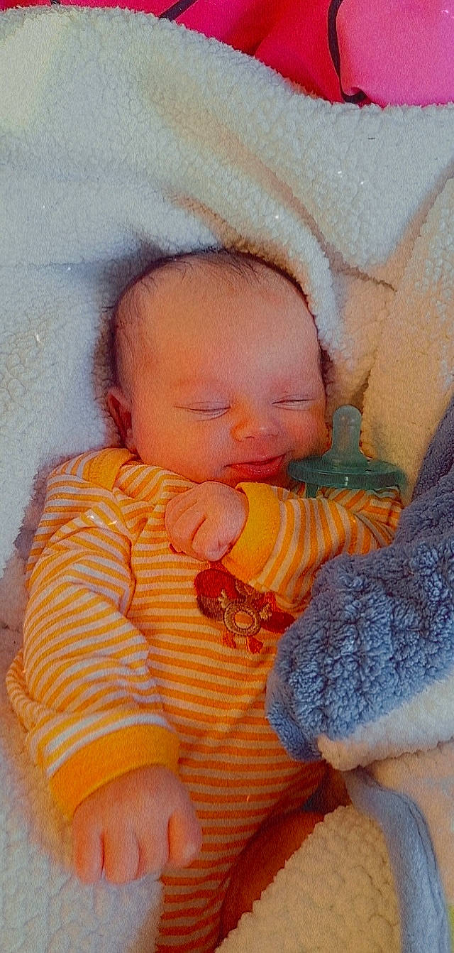 Prince is registered to the contest to win money with this photo: abdomen, baby, baby_toddler_clothing, cheek, child, chin, comfort, eye, facial_expression, finger, human_body, iris, linens, lip, mouth, nose, orange, person, skin, toddler