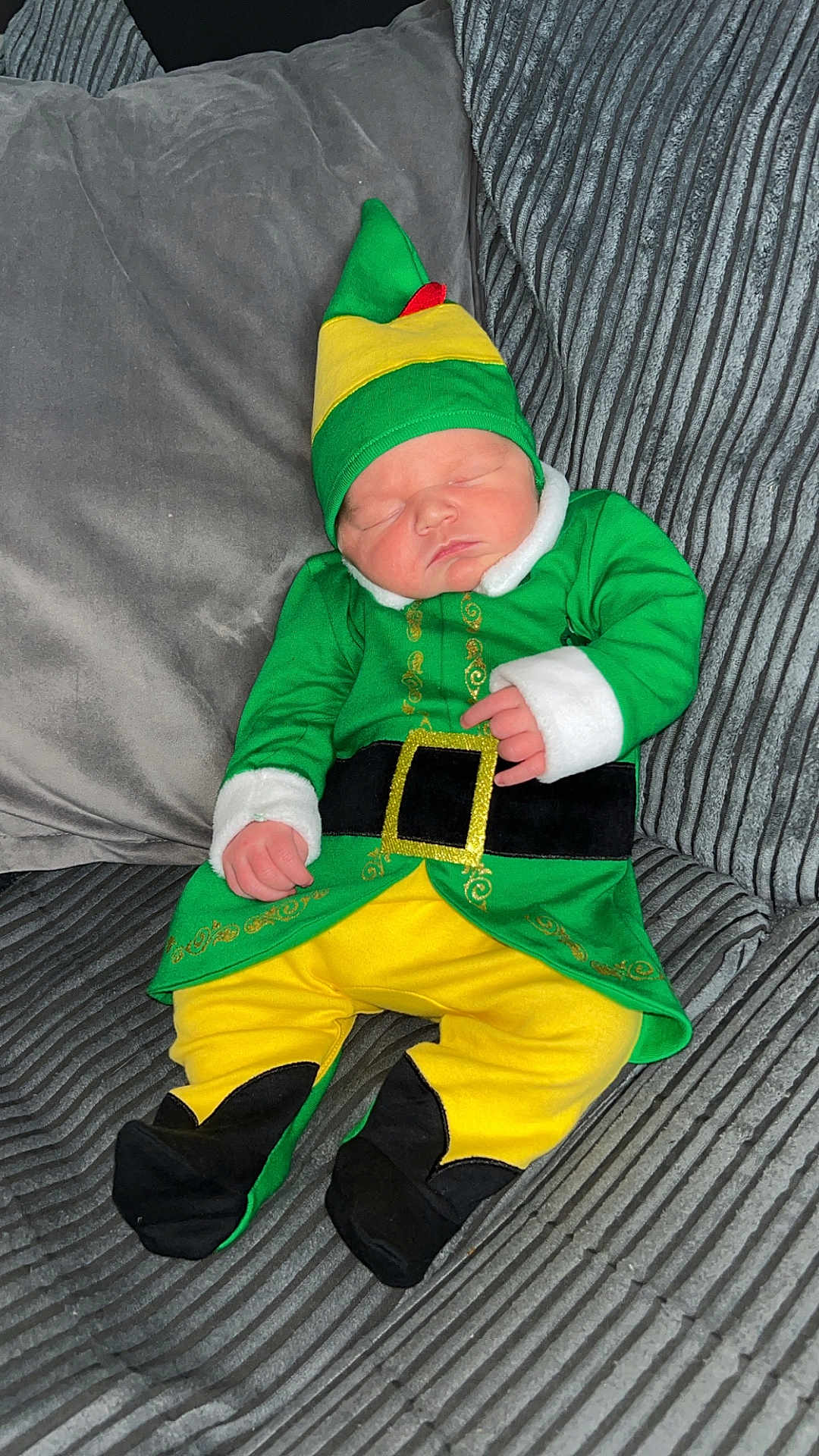 Maxx is registered to the contest to win money with this photo: baby, child, sleeping, costume, elf, green_clothing, yellow_clothing, hat, couch, pillow, indoor, infant, cute, resting, soft_fabric, home, person, portrait, cozy, holiday