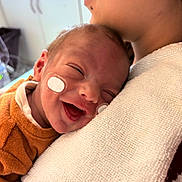 Leyvone a rejoint le concours — aidez-le/la à gagner de superbes lots ! newborn, baby, infant, smiling, adult, parent, holding, cuddle, hug, medical_patch, adhesive_tape, hospital, burp_cloth, white_towel, orange_clothing, closeup, portrait, cheek, happy, skin
