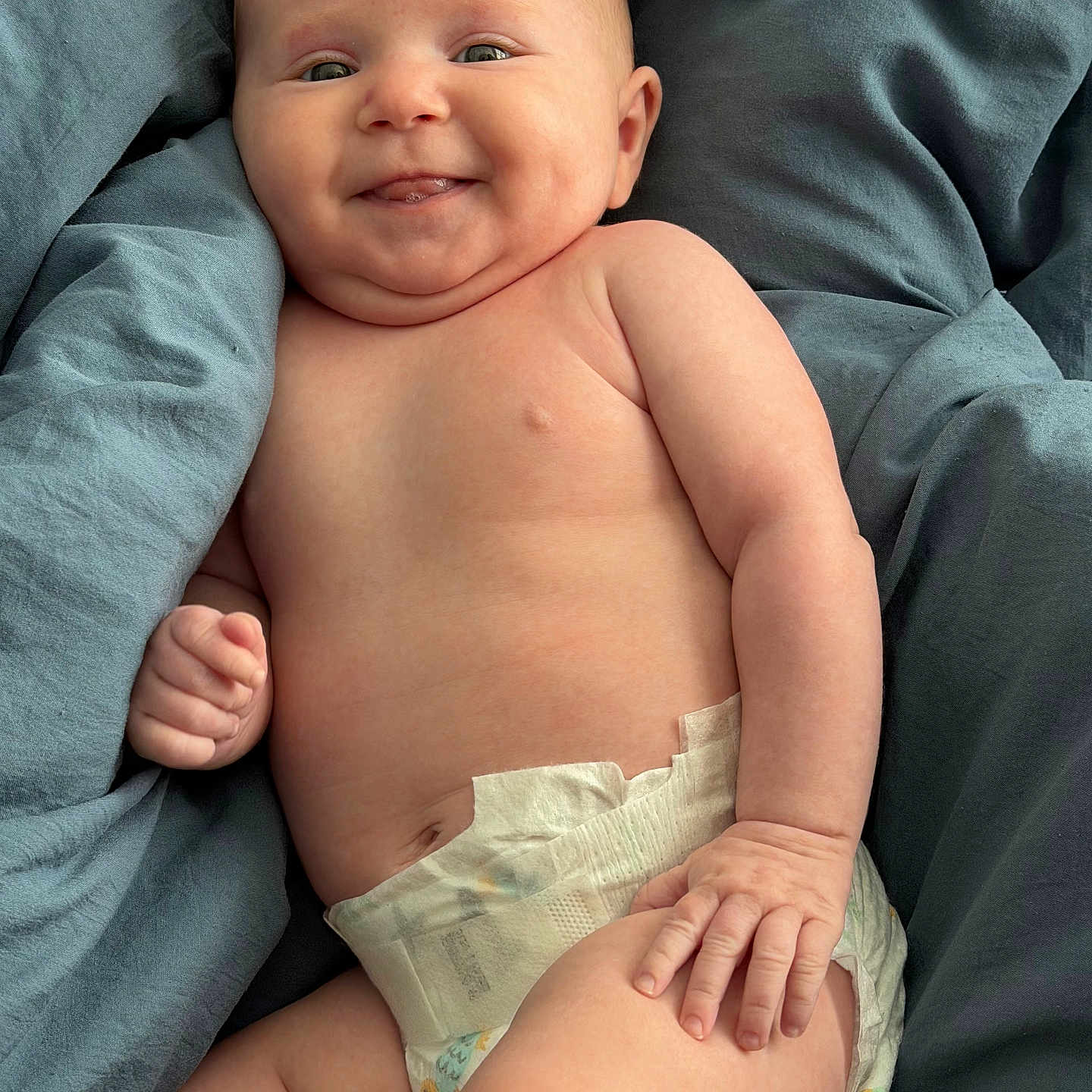 Elizabeth joined the competition — help win amazing prizes! baby, infant, smile, diaper, dimples, skin, hand, leg, blanket, blue, cute, chubby, lying_down, portrait, face, happy, child, soft, comfort, indoors