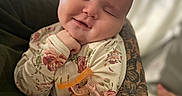 Elizabeth is registered to the contest to win money with this photo: baby, infant, smile, closed_eyes, floral_pajamas, tattoo, arm, hand, blanket, pacifier_clip, cozy, sleepy, cute, child, portrait, indoor, soft_light, person, skin, comfort