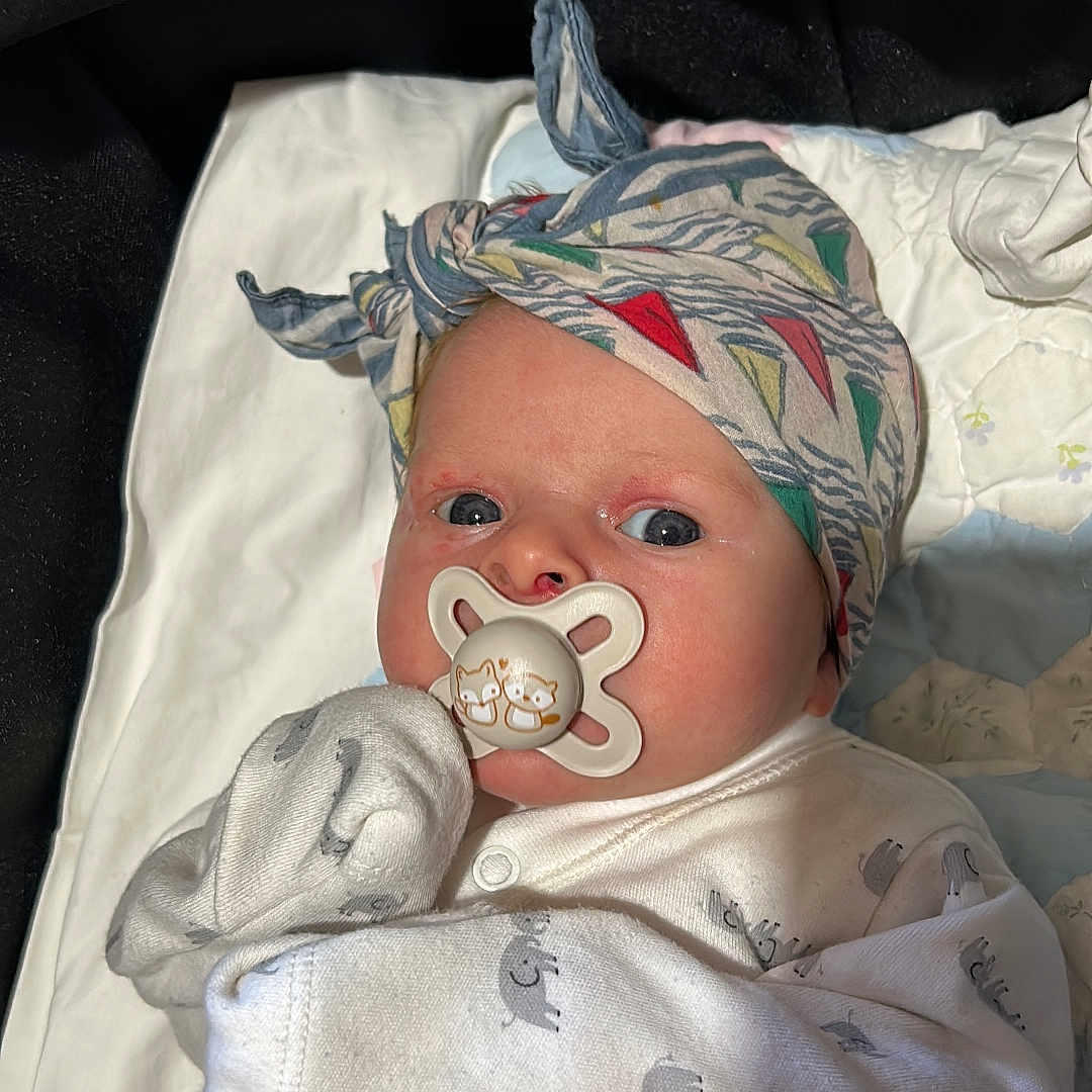 Scarlett is registered to the contest to win money with this photo: baby, bed, beverage, bonnet, cap, clothing, coffee, coffeecup, cushion, face, furniture, hat, head, homedecor, newborn, person, photography, portrait, skin, tattoo