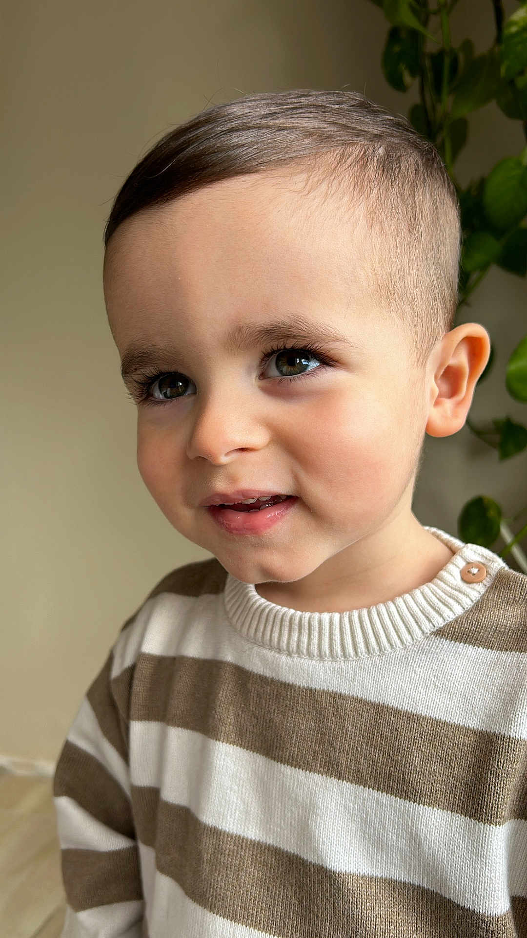 Noah a rejoint le concours — aidez-le/la à gagner de superbes lots ! child, toddler, portrait, face, smiling, eyes, sweater, striped_clothing, brown_hair, indoor, plant, greenery, cute, young, person, head, expression, skin, button, casual_wear