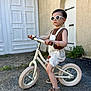 toddler, child, balance_bike, sunglasses, overalls, sneakers, outdoor, concrete, door, wall, plant, summer, casual, fashion, young_child, play, portrait, side_view, cool, confident
