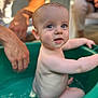 adult_hand, baby, bath, blue_eyes, care, child, closeup, cute, human, indoor, infant, naked, parent, person, playful, sitting, skin, smile, tub, water