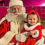 child, santa_claus, christmas, holiday, festive_clothing, red_dress, white_fur_trim, girl, beard, glasses, smile, indoor, decorations, lights, headband, black_shoes, jeans, gloves, portrait, happy