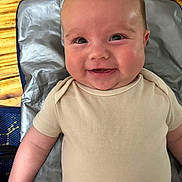 Landon joined the competition — help win amazing prizes! baby, smile, infant, face, eyes, cheeks, clothing, onesie, arm, skin, lying_down, mat, floor, wood, happy, cute, portrait, child, person, indoors