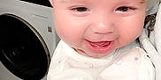 Landon joined the competition — help win amazing prizes! baby, smiling, infant, face, onesie, moon_pattern, stars_pattern, human, indoor, laundry_room, washing_machine, dryer, floor_tiles, closeup, happy, cute, skin, person, hand, soft