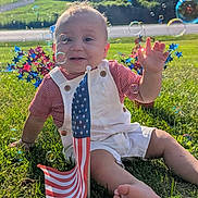 Zion is registered to the contest to win money with this photo: baby, bubbles, child, field, flag, garden, grass, infant, outdoor, overalls, patriotic, portrait, road, smiling, striped_shirt, summer, sunlight, tie, trees, waving