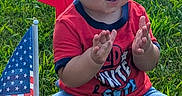 Zion joined the competition — help win amazing prizes! american_flag, baby, blue_shorts, child, clapping, daylight, face, feet, grass, hands, infant, lawn, outdoor, patriotic, portrait, red_shirt, road, sitting, smiling, star_decoration