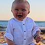 baby, beach, casual, child, cute, happy, infant, nature, ocean, outdoor, portrait, sand, sitting, smiling, sunlight, sunset, vacation, waves, white_shirt, young_child
