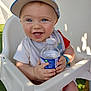 Louka a rejoint le concours — aidez-le/la à gagner de superbes lots ! baby, blue_eyes, cap, child, cute, daylight, grass, happy, high_chair, holding, infant, outdoor, person, playful, short_sleeves, smiling, summer, sunlight, water_bottle, white_chair