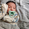 baby, bed, blanket, child, clothing, comfort, cozy, cute, face, hand, indoor, infant, newborn, onesie, pacifier, pattern, portrait, resting, sleeping, soft