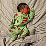 newborn, baby, sleeping, onesie, green_clothing, football_pattern, blanket, soft_texture, infant, cute, peaceful, indoors, portrait, child, resting, cozy, clothing, young, sleep, babywear