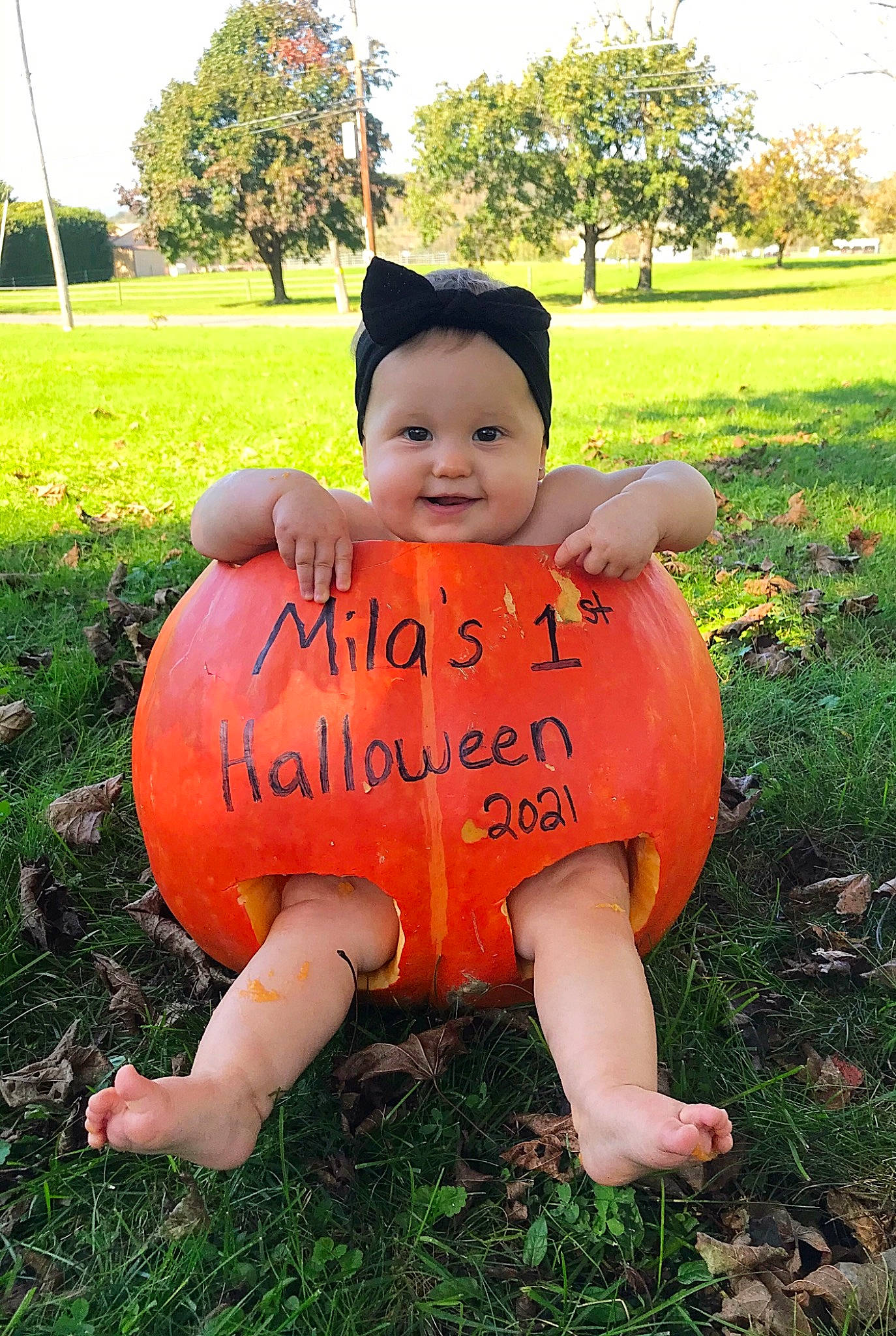 Mila is registered to the contest to win money with this photo: baby_toddler_clothing, facial_expression, fun, grass, grassland, happy, hat, headwear, joy, leisure, mammal, natural_environment, nature, people, people_in_nature, person, plant, pumpkin, smile, summer