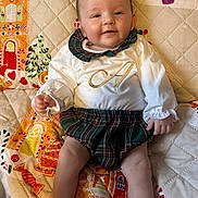 Alba joined the competition — help win amazing prizes! baby, child, colorful, cozy, cute, face, festive, hands, happy, indoors, infant, legs, patterned, plaid_skirt, portrait, quilt, sitting, smiling, soft, white_clothing