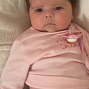 Annie is registered to the contest to win money with this photo: baby, infant, pacifier, pink_pajamas, blanket, sleepwear, face, expression, child, newborn, cute, lying_down, soft_texture, indoor, skin, hand, head, clothing, comfort, resting