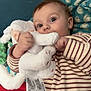 baby, child, stuffed_animal, toy, pajamas, striped_clothing, hand, face, eyes, blanket, blue_background, soft_toy, cuddly, infant, cute, portrait, indoor, comfort, bed, relaxation