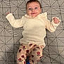 Léna participe au concours pour gagner de l'argent avec cette photo : baby, smiling, infant, lying_down, sweater, floral_pants, blue_socks, bed, geometric_pattern, black_and_white, cute, happy, child, indoor, portrait, clothing, person, young_child, patterned_bedspread, cozy
