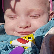 Sophia is registered to the contest to win money with this photo: baby, infant, face, closed_eyes, smile, hat, shadow, clothing, blue_outfit, pacifier_clip, sunlight, skin, headwear, cute, child, portrait, happy, young, indoors, close_up